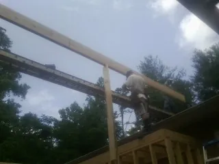 Carpenter setting a ridge beam over a new addition frame — Ice Dam Removal by Roofing Brothers in Wyatt