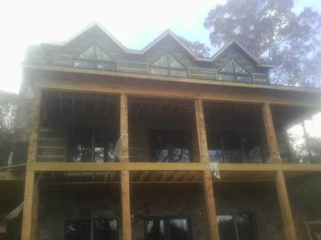 Dormers and porch framing on a large log home under construction — Roof Coating work by our crew in Wyatt