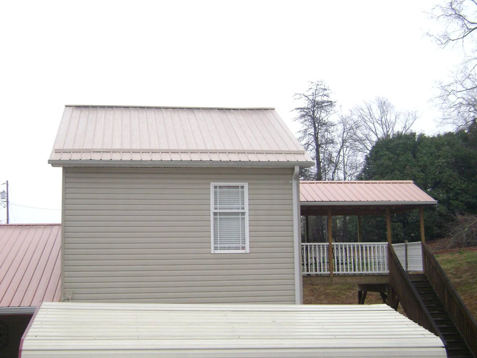 Tan metal roofs on a two story addition and attached porch, from a Roof Replacement job in Wyatt