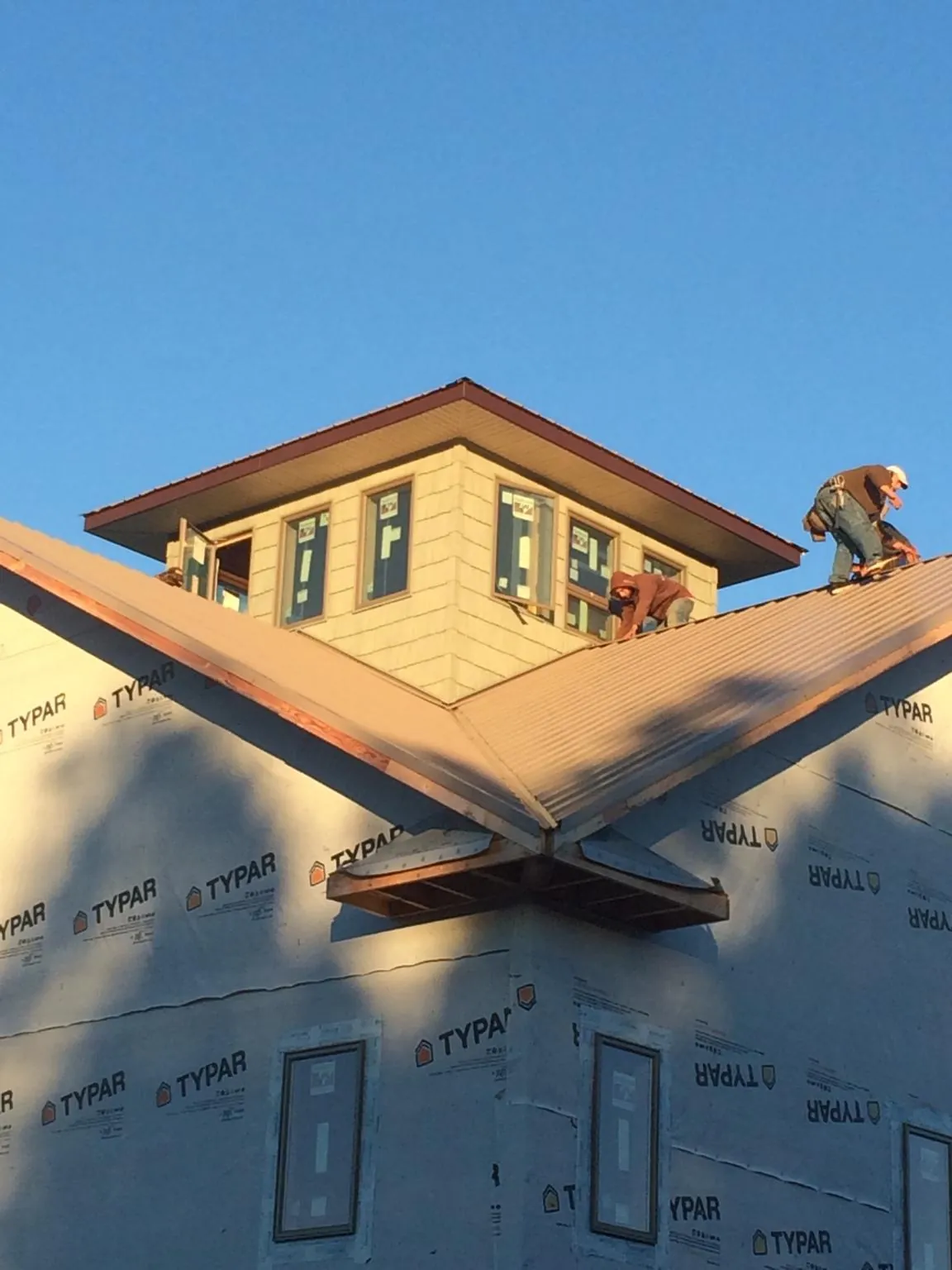 Roofers working around a rooftop cupola on a new metal roof at sunset — Roof Waterproofing in Wyatt by Roofing Brothers